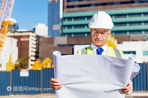 建筑工地的工程师建设者工程师建筑工人施工场景穿着带蓝图的安全背心